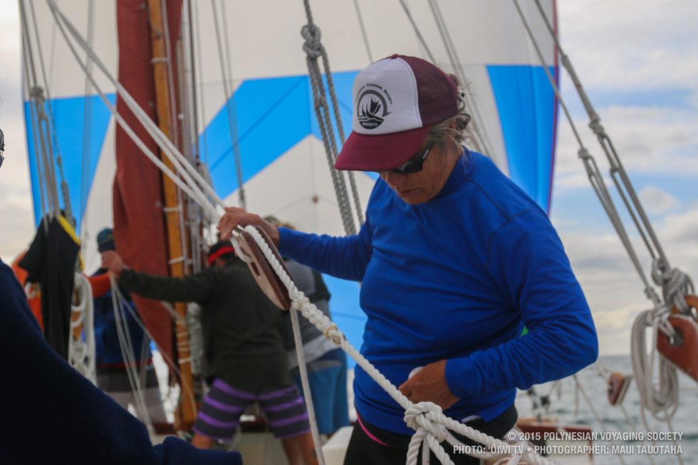Hauʻoli cleaning up sheet lines while the spinnaker flies in the background.